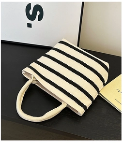 Close-up of minimalist striped canvas handbag with thick rope handles and woven texture
