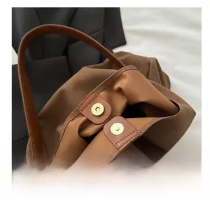 Detail view of the vintage tote bag's gold magnetic closure and leather strap