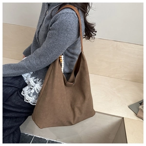 Detail of a large brown suede tote bag with leather strap and decorative beads