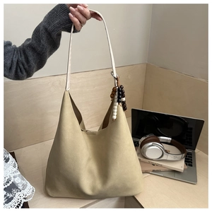Close-up of khaki tote bag with beaded pendant in a minimalist office setting