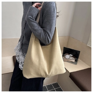 Detailed view of beige faux suede tote bag worn over the shoulder in a lifestyle setting