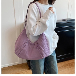 Close-up of purple pleated nylon tote bag worn on shoulder by model in casual setting