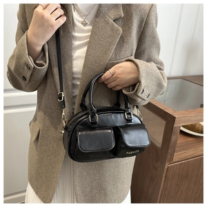 Detailed view of black vintage pillow bag with dual front pockets and fashion text