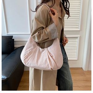Detail showing soft pleated texture of light pink nylon crescent commuter shoulder bag