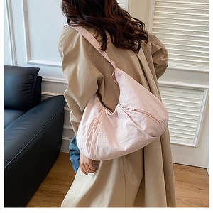 Detail of light pink large nylon crescent bag showing the adjustable shoulder strap and texture