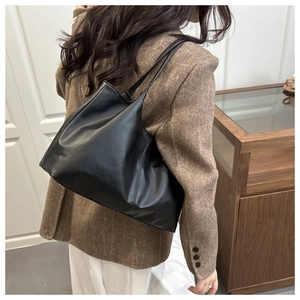 Detail view of large black PU leather tote bag worn by model for daily commuting fashion