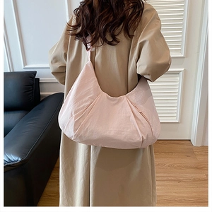 Detail of a large pink shoulder bag with pleated nylon fabric and a wide strap on a model