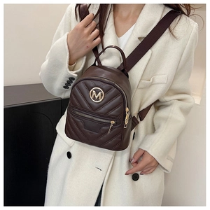 Detail of a brown quilted mini backpack with M logo and stylish wide shoulder strap