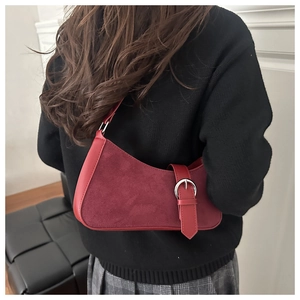 Détail du sac bandoulière bordeaux avec boucle argentée sur texture daim et cuir
