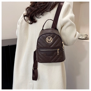 Close-up of dark brown quilted leather mini backpack with gold M hardware and V stitching