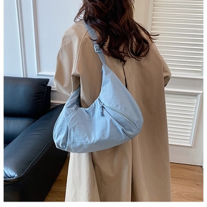 Detail of light blue nylon crescent bag with adjustable strap and textured fabric surface