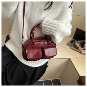 Close-up of wine red PU leather handbag with gold zipper and dual front flap pockets