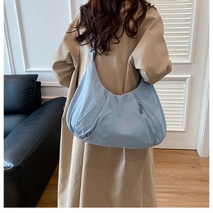 Model view of a large light blue crescent tote bag with soft pleated nylon texture