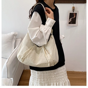 Detailed view of the off-white pleated hobo bag worn over the shoulder by a model