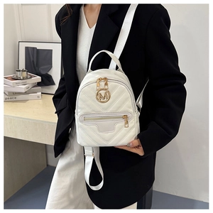 Detail of white quilted mini backpack with gold M logo and dual zipper compartments