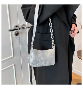 Silver metallic pleated crescent bag with chain strap detail on black coat model