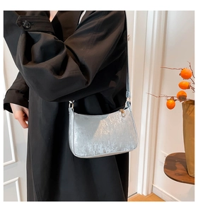 Close-up of metallic silver hobo bag with vertical texture worn with a black coat