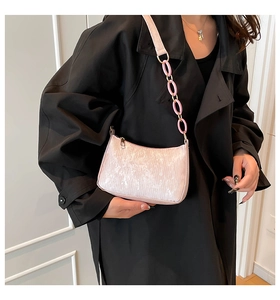 Pink sequined shoulder bag with acrylic chain detail shown on a black trench coat