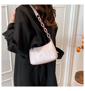 Detail of pink pearlescent shoulder bag with stylish thick chain on a female model