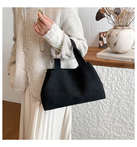 Close-up of black suede tote bag texture with minimalist double handles and matte finish