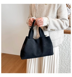 Minimalist black matte trapezoid handbag styled with a white pleated skirt for women