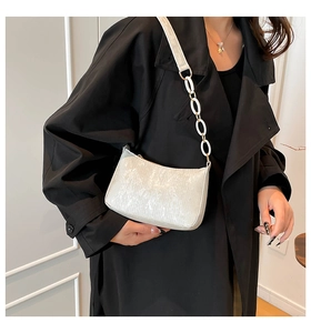 Detail of silver shiny hobo bag with white circular chain strap on black coat
