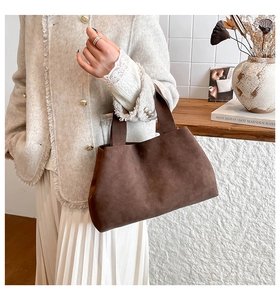 Detail shot of brown suede tote bag featuring a minimalist trapezoid shape and thick handle