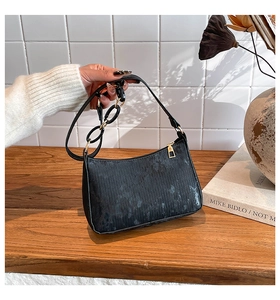 Detail of vintage black faux leather underarm bag with gold zipper and chain strap