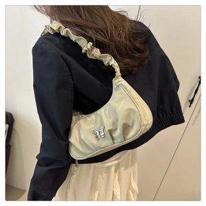 Detail of light green pleated shoulder bag with satin finish and metal butterfly ornament