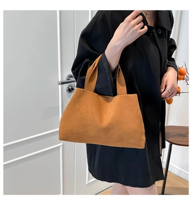 Close-up of brown suede tote bag with wide handle showing soft minimalist texture