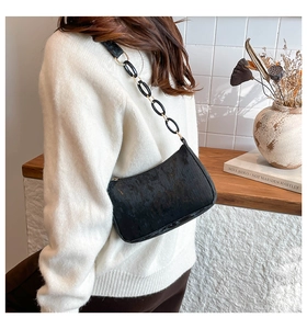 Close-up of black corduroy shoulder bag with elegant oval ring and metal chain strap