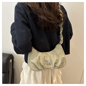 Detail of light green pleated moon bag with silver butterfly and scrunchie strap