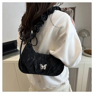 Detailed view of black pleated moon bag with silver butterfly and ruffled shoulder strap