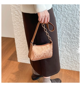 Detail of bronze textured velvet baguette bag with elegant metallic chain and leather strap