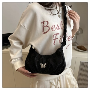 Detail of black pleated crescent bag with silver bow and ruffled shoulder strap on model