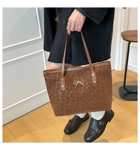 Detail of leopard print tote bag with golden bow buckle and premium leather texture
