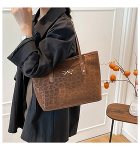 Leopard print tote bag with gold bow detail and metallic studs shown on model shoulder