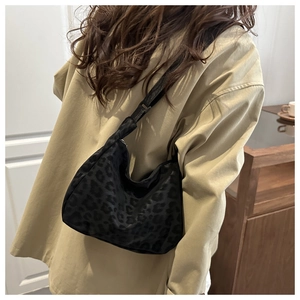 Back view of model wearing a large black leopard print hobo bag with nylon strap