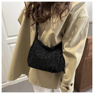 Side view of dark leopard print hobo bag with nylon strap shown on a female model