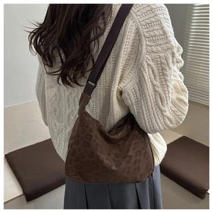 Detail shot of leopard print shoulder bag worn with casual outfit in minimalist interior