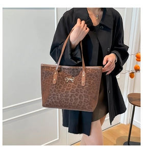 Detailed view of leopard print tote bag with elegant golden bow decoration on the front