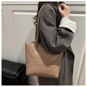 Side view of large light brown faux leather tote bag with embossed brand text on model