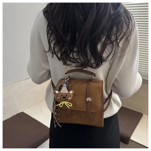 Detail of brown faux suede backpack with metal buckle and cute teddy bear pendant charm