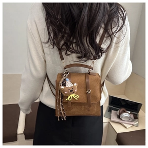 Close-up of brown suede mini backpack with vintage flap and cute plush bear charm