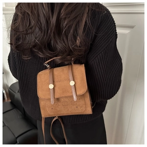 Detailed view of a brown suede mini backpack featuring cute bear motifs and flap straps