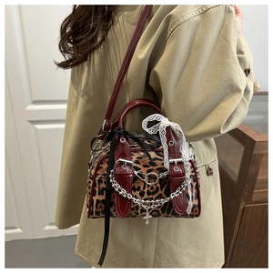 Detailed side view of leopard print crossbody bag with red trim and lace bow detail