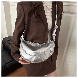 Detail of silver half-moon crossbody bag with metallic texture and knotted rope strap