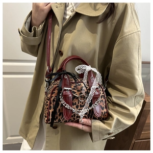 Detail of leopard print handbag with leather trim, lace bows, and silver chain strap