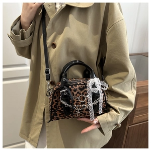 Detail of leopard print handbag featuring silver chain and white lace bow decoration