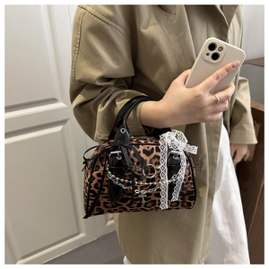 Detail of leopard print Boston bag featuring silver chain cross and white lace trim